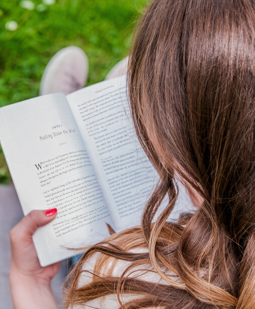 Back view of a woman outside reading a book.